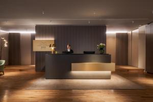 a woman sitting at a counter in a lobby at Palazzo Porta Romana Hotel in Milan