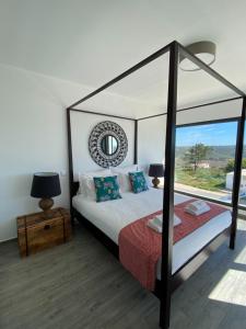 ein Schlafzimmer mit einem Himmelbett und einem Fenster in der Unterkunft Cairnvillas: Villa Terra C39 - Luxury Villa with Private Swimming Pool near Beach in Aljezur