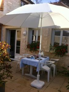 a table with an umbrella in front of a house at Les Rainettes in Coye-la-Forêt