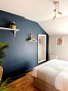 1 dormitorio con pared azul, cama y espejo en 'Bridgewater' at stayBOOM, en Morecambe