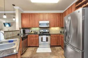 a kitchen with wooden cabinets and a stainless steel refrigerator at Modern Condo near Texas Medical Center w Free Parking in Houston