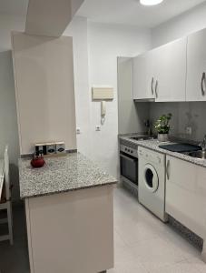 a kitchen with white cabinets and a washer and dryer at APARTAMENTO EN LOS GALLOS in Chiclana de la Frontera