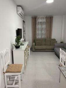 a living room with a couch and a table with a tv at APARTAMENTO EN LOS GALLOS in Chiclana de la Frontera