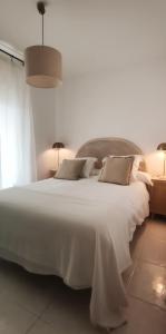 1 dormitorio con 1 cama blanca grande y 2 lámparas en Los Castellanos nº 8 Suances, en Suances