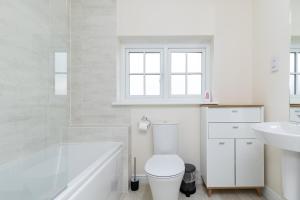 La salle de bains blanche est pourvue de toilettes et d'un lavabo. dans l'établissement Wakefield, 5 Minutes from Centre & Motorways - Free Parking & Wi-Fi, Self Check-in, King Size Beds, En-suite Bedrooms - Contractors Welcome, à Wakefield
