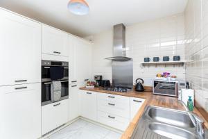 a kitchen with white cabinets and a stainless steel sink at Wakefield 4 Bed - Parking, Self Check-in, Fast WiFi, Near Centre, Motorway Access - Contractors, Families, Long Stays in Wakefield