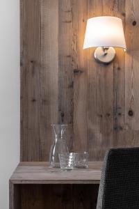un vaso e dei bicchieri su un tavolo di legno con una lampada di Hotel Krondlhof a Brunico