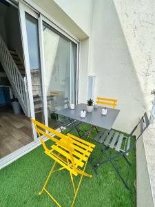 2 gelbe Stühle und ein Tisch auf dem Balkon in der Unterkunft Le Petit Canada - Proche ville in La Rochelle