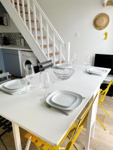 einen weißen Tisch mit Tellern und Weingläsern darauf in der Unterkunft Le Petit Canada - Proche ville in La Rochelle