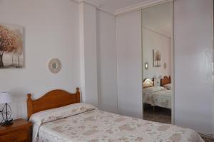 科尼爾－德拉弗龍特拉的住宿－Aptº ATALAYA , junto a la Playa，白色卧室配有床和镜子