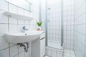 a white bathroom with a sink and a shower at Burg Rotraut #6 in Ostseebad Sellin +6 photos