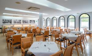 a restaurant with white tables and chairs and windows at Medplaya Hotel Monterrey in Platja d'Aro