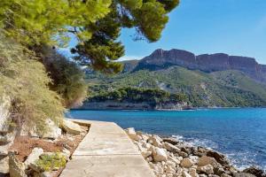 a path leading to a body of water with mountains at Un balcon, au cœur du village in Cassis