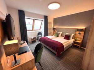 シュターデにあるHotel Garni am Obsthof GbRのベッドとデスクが備わるホテルルームです。