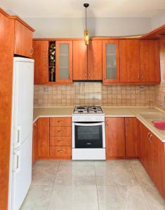 cocina con armarios de madera y horno de fogón blanco en City View Apartment, en Kavala