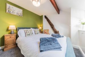 1 dormitorio con cama y pared verde en Byre & Millers Woodland Coniston Sleeps 12, en Torver