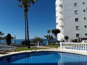 una piscina di fronte a un edificio con palme di Algaida New Studio Calahonda, Beach, Pools and Garden a Sitio de Calahonda