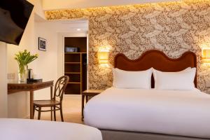 a bedroom with a bed and a desk and a chair at Hotel Michelet Odeon in Paris