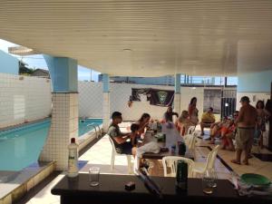 un grupo de personas sentadas alrededor de una mesa junto a una piscina en Casa Vista do Mar, praia e piscina, en Vila Velha