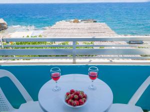 a table with two glasses of wine and a bowl of strawberries at Klima Rooms in Palaiochóra