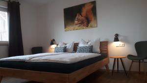 Hof Schütterle في فريدريشسهافن: غرفة نوم مع سرير مع لوحة aulture على الحائط