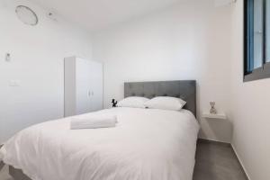 een witte slaapkamer met een groot bed met witte lakens en kussens bij O&O Group - Luxury APT/3 BR/New Tower/Parking in Or Yehuda