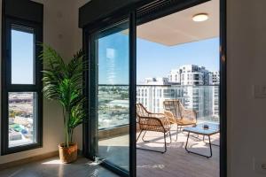 a balcony with chairs and a potted plant at O&O Group - Luxury APT/3 BR/New Tower/Parking in Or Yehuda