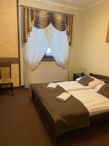 two beds in a hotel room with a window at Willa Bella in Zakopane