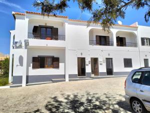 een wit huis met een auto voor de deur bij 2 Quinta Lamy - Casas & Papéis in Porches