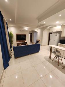 Sama Residence في الخبر: غرفة معيشة مع أريكة زرقاء وطاولة