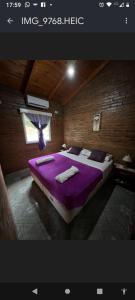 a bedroom with a bed with purple sheets and a window at Mi Buen Refugio in Puerto Iguazú
