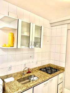 a white kitchen with a sink and a stove at Flats Residence Bueno in Goiânia