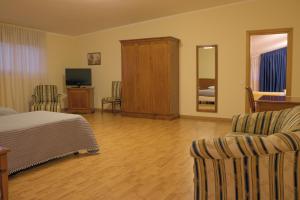 - une chambre avec un lit, deux chaises et une télévision dans l'établissement Ruggiero Park Hotel, à Vallo della Lucania
