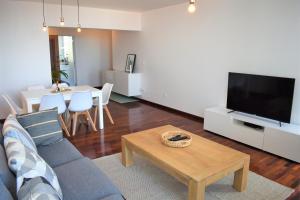 uma sala de estar com um sofá, uma televisão e uma mesa em Madeira, 3 bedroom apartment with ocean views in Funchal no Funchal