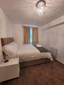 a bedroom with a large bed and a chandelier at Tastefully decorated 1 bed flat near AbbeyWood in Belvedere