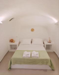 a white bedroom with two towels on a bed at Finikas Cave House in Foinikiá +52 photos