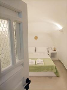 a white room with a bed and a window at Finikas Cave House in Foinikiá