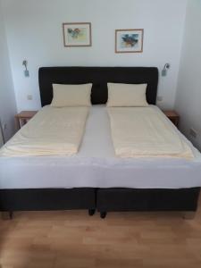 - un lit avec un cadre noir et des draps blancs dans l'établissement Appartement Huber, à Lutzmannsburg