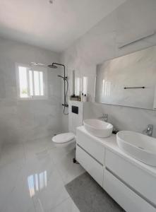 a white bathroom with two sinks and a toilet at Celebrate Life's Precious Moments at Can Saca! in Sant Jordi