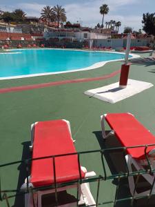 einem roten Stuhl neben einem Pool in der Unterkunft House Camping Pasito Blanco in Maspalomas