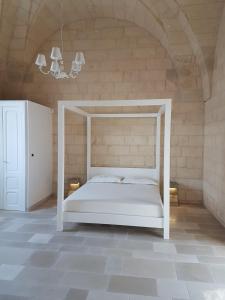 un letto bianco in una stanza con un muro di mattoni di Masseria "Casa Giulia" a Uggiano la Chiesa