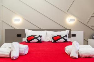 Incantos charme B&B في تورتولي: غرفة نوم بسرير احمر مع شراشف ووسائد بيضاء