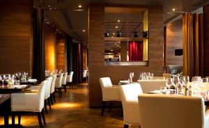 a dining room with tables and white chairs at Aviator in Farnborough