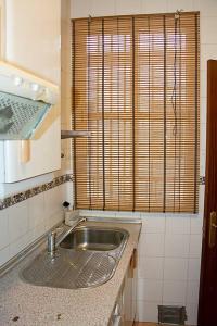 Elle comprend une petite cuisine avec un évier et une fenêtre. dans l'établissement Apartamento Calle Feria, à Séville
