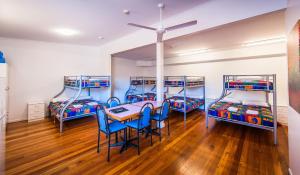 three bunk beds in a room with a table and chairs at Diggers Tavern in Bellingen