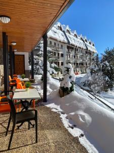 a patio with a table and chairs in the snow at Hotel Tirol in Formigal
