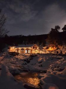 ein Haus wird nachts im Schnee beleuchtet in der Unterkunft Billingen Seterpensjonat in Skjåk