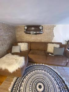 sala de estar con sofá marrón y pared de ladrillo en CASASTASIA HOME, en Torre del Greco