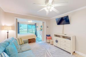 ein Wohnzimmer mit einem Sofa, einem TV und einem Bett in der Unterkunft Sunset Harbor Palms 2 102 Luzviminda Cove in Navarre