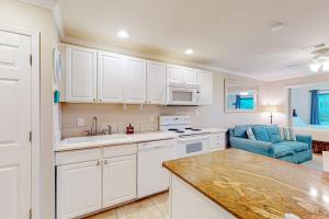 eine Küche mit weißen Schränken und einer blauen Couch in der Unterkunft Sunset Harbor Palms 2 102 Luzviminda Cove in Navarre